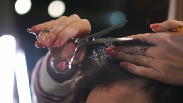Primer-plano,-maestro-peluquero-hace-peinado-y-estilo-con-tijeras-y-peine.-Concepto-de-barbería