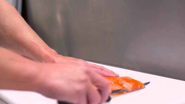 männlichen-Chef-schneiden-geräucherten-Lachsfilet-in-Restaurantküche