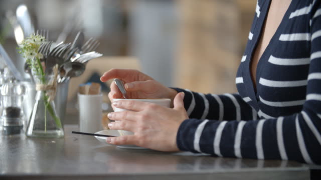 Nahaufnahme-von-Frauenhand-rühren-Tasse-Kaffee-in-einem-café