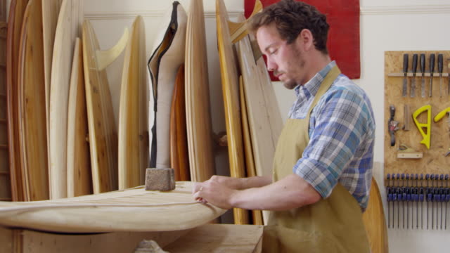 Hombre-construyendo-tabla-de-surf-personalizada-en-el-taller-filmado-en-la-cámara-roja