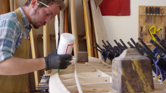 Hombre-glueing-Custom-tabla-de-surf-en-el-taller-de-tiro-en-la-cámara-roja