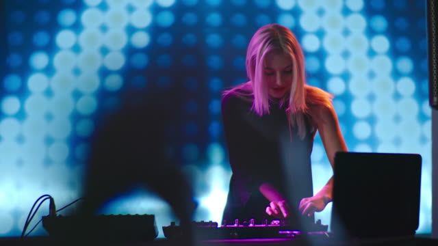 DJ-mujer-rubia-bailando-detrás-de-mezclador