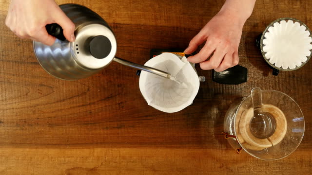 Barista-pouring-water-on-coffee-ground-with-filter