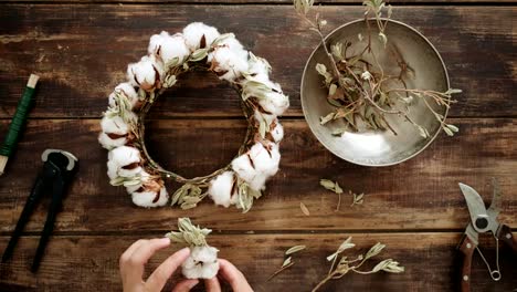 Top-view-on-woman-work-on-wreath-at-wood-table