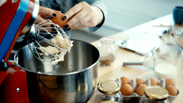 Close-up-view-of-young-female-hands-mixing-the-ingredients-in-big-bowl-with-mixer.-Female-cooking-on-the-kitchen