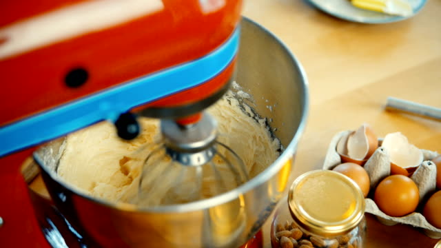 Close-up-view-of-red-mixer-blending-the-dough,-ingredients-in-big-bowl.-Confectioner-cooking-the-desserts