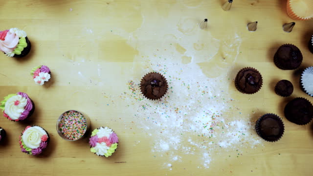 Draufsicht-der-jungen-weiblichen-Händen-Verzierung-die-Schokolade-Cupcake-oder-Muffin-mit-Sahne,-mit-Spritzbeutel-für-diese