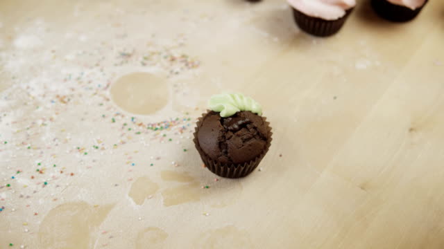 Vista-de-primer-plano-de-manos-femeninas-decorar-el-cupcake-de-chocolate-con-color-crema,-con-Manga-pastelera-para-esto