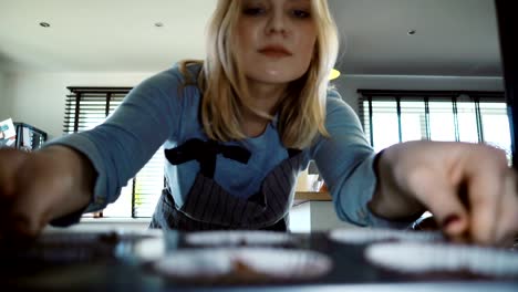 View-inside:-young-beautiful-woman-opens-the-oven-and-puts-in-the-baking-tray-with-cupcakes.-Female-cooking-at-home