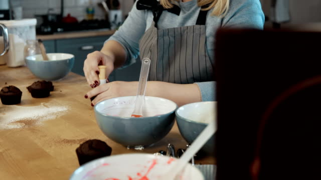 Junge-blonde-Frau-die-Cupcakes-in-der-Küche-kochen.-Schöne-Frau-mit-dem-Cuttermesser-zu-Muffins-machen