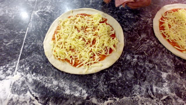 Pizza-preparation,-applying-salami-on-dough,-top-view