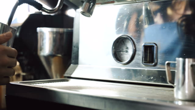 Barista-cociendo-al-vapor-la-leche-en-el-vaso-de-metal