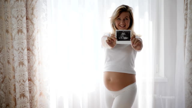 Mutterschaft,-schwangere-Frau-halten-Ultraschall-Scan-Säugling-neben-nackten-schwangeren-Bauch
