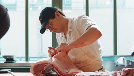 Joven-hombre-carnicero-preparando-cuidadosamente-un-corte-grande-de-carne
