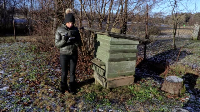 Female-beekeeper-inspecting-beehive-in-winter