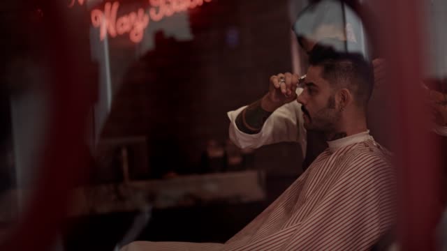 Man-getting-haircut-by-stylish-barber-in-old-fashioned-barber-shop