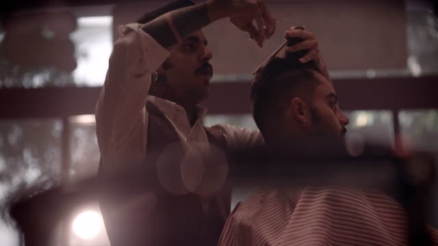 Young-stylish-barber-cutting-man's-hair-in-vintage-barber-shop