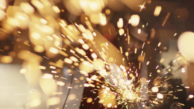 Powerful-young-woman-using-grinder-and-sparks-flying-impressivly-into-camera