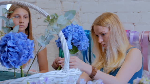 Zwei-Frauen-Floristen-machen-große-Blumenkorb-mit-Blumen-im-Blumenladen