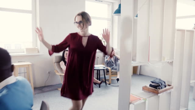 Camera-follows-European-female-boss-exiting-multi-ethnic-modern-office,-doing-crazy-dance-walk-of-success-and-victory-4K
