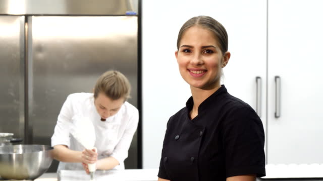 Chef-mujer-feliz-sonriendo-mostrando-los-pulgares-para-arriba-en-la-cocina
