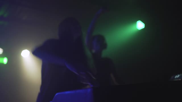 Dos-hermosas-mujeres-jóvenes-DJ-juegan-la-música-en-la-mesa-de-mezclas-en-la-discoteca