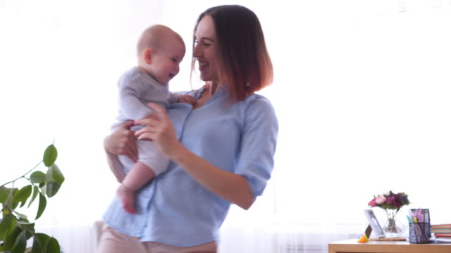 Cheerful-girl-playing-with-little-baby-dancing-together