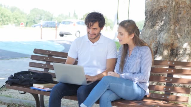 einige-junge-Studenten-Mann-und-Frau-gemeinsam-mit-Laptop-Computer-in-einer-Straße-im-Freien-im-Sommer