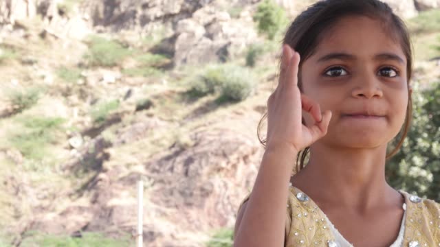 Little-cute-Indian-girl-making-hand-gestures-towards-the-camera-sayng-good-or-ok