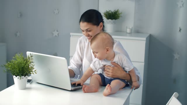 Young-mother-working-with-laptop-at-home