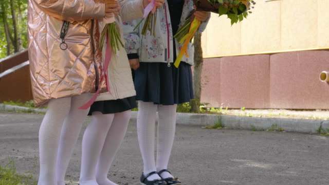 Adorable-female-schoolchildren-with-flowers,-crane-shot