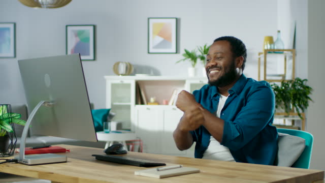 Portrait-of-the-Handsome-African-American-Man-Dancing-while-Sitting-at-His-Workplace.-Young-Man-Having-Fun-at-Home.-In-Slow-Motion.
