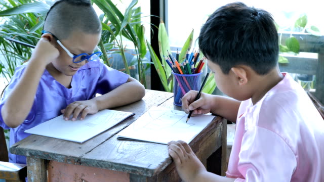 Feliz-niño-Asiático-con-escribir-en-el-cuaderno-y-lápices-de-dibujo-en-casa.-concepto-de-educación