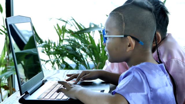 Feliz-muchacho-asiático-dos-personitas-con-ordenador-portátil.