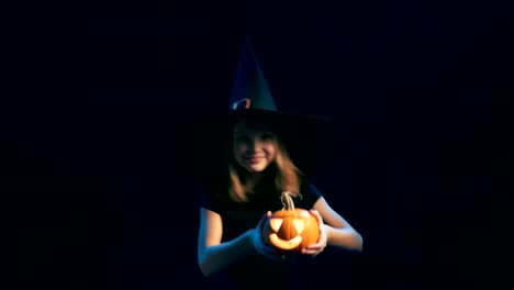 Girl-wearing-black-witch-hat-holding-jack-o'-lanterns