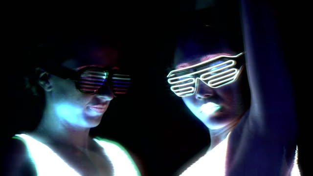 Women-with-UV-face-paint,-glowing-clothing,-glowing-bracelet,-glasses-dancing-in-front-of-camera,-face-shot.-Caucasian-and-woman.-Glitch-effects.-Women.