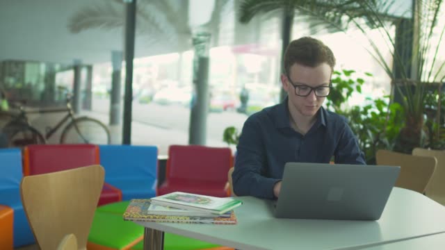 Junger-Mann-arbeitet-mit-Laptop-in-der-Bibliothek
