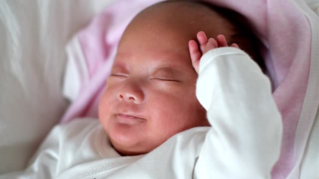 Neugeborenes-Babymädchen-im-Kinderbett-liegend-wacht-auf-und-erstreckt-sich
