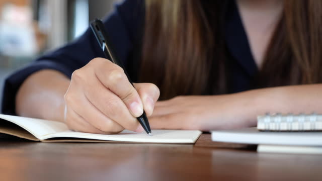 Eine-Frau-auf-einem-weißen-leeren-Notebook-auf-Tabelle-aufschreiben