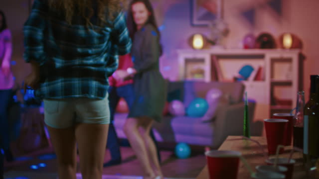 At-the-College-House-Party:-Diverse-Group-of-Friends-Have-Fun,-Dancing-and-Socializing.-Boys-and-Girls-Dance-in-thr-Circle.-Girl-Takes-Glass-with-Drink-from-the-Tray-and-Joins-the-Group.