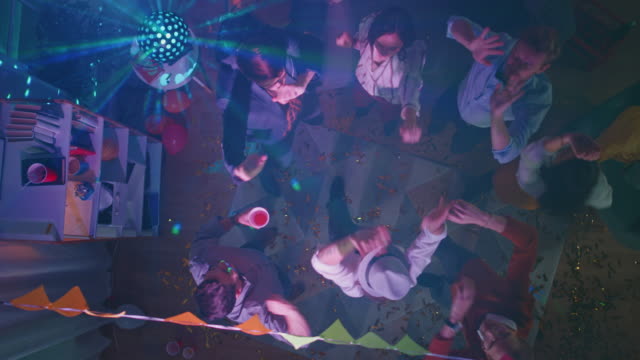 Bei-der-College-Party:-vielfältige-Gruppe-von-Freunden-Spaß-haben,-tanzen,-Kontakte-zu-knüpfen-und-zu-trinken.-Stilvolle-junge-Menschen-Tanz-energisch-im-Wohnzimmer.-Disco-Neon-Lichter.-Top-Down-Schuss.