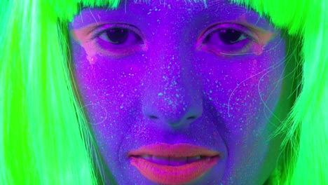 Closeup-woman-face-with-fluorescent-make-up-in-green,-wig,-creative-makeup-look-great-for-nightclubs.-Halloween-party,-shows-and-music-concept---slow-motion-video