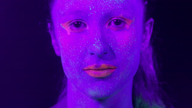 Closeup-woman-face-with-fluorescent-make-up,-creative-makeup-look-great-for-nightclubs.-Halloween-party,-shows-and-music-concept---slow-motion-video