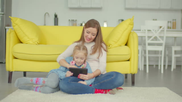 Carefree-mom-and-girl-playing-online-with-tablet-pc