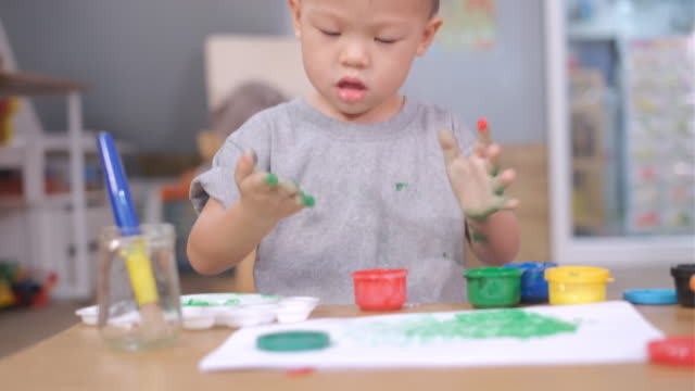 Asian-2--3-years-old-toddler-baby-boy-child-finger-painting-with-hands-and-watercolors