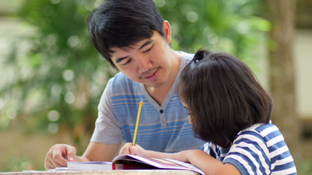 Little-Asian-girl-con-padre-haciendo-los-deberes-en-la-tabla