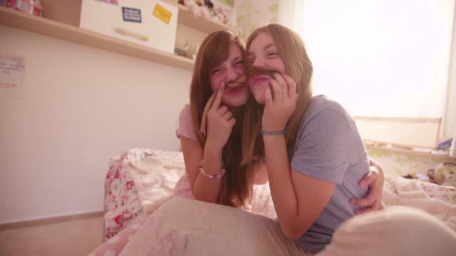 Mädchen-auf-einem-Bett-halten-einander\'s-hair-wie-wegen-Schnurrbärte