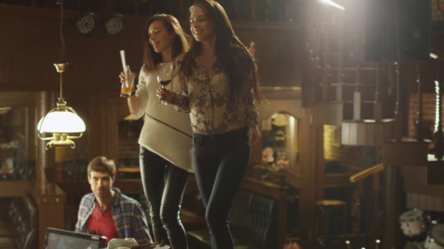 Dos-niñas-son-bailando-con-bebidas-en-una-mesa-que-todo-el-mundo-tiene-un-buen-tiempo-juntos-en-un-bar.