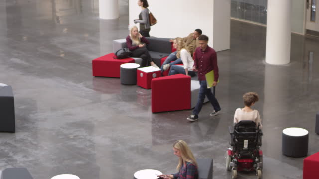 Schüler-entspannen-gemeinsam-in-der-Lobby-einer-belebten-Universität,-Schüsse-aufs-R3D
