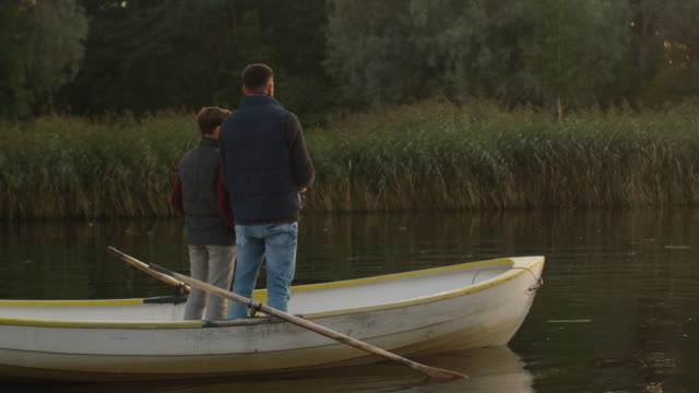Father-and-Son-are-Standing-in-the-Boat-and-Fishing.